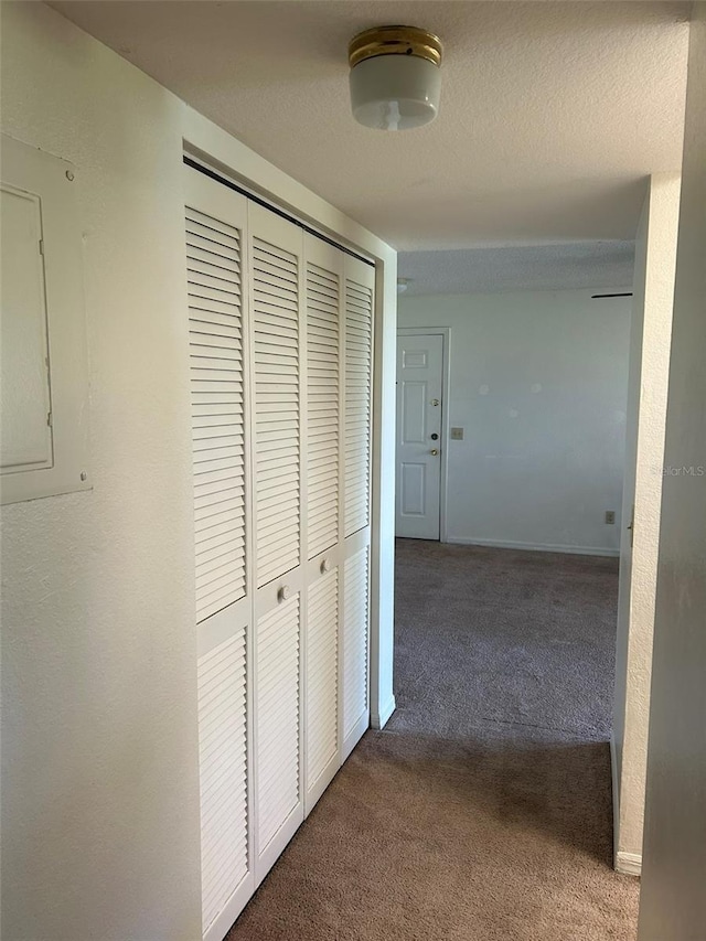 hallway with carpet floors, electric panel, baseboards, and a textured ceiling