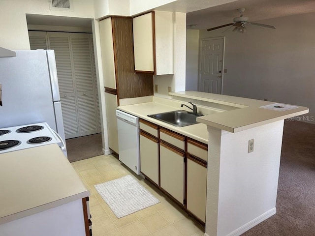 kitchen featuring a peninsula, white appliances, light countertops, and a sink