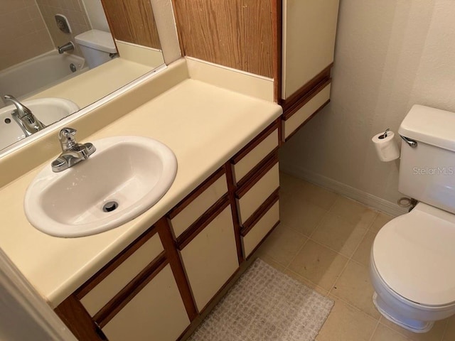 bathroom featuring baseboards, toilet, a tub, tile patterned flooring, and vanity