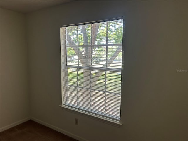 empty room with baseboards and dark colored carpet