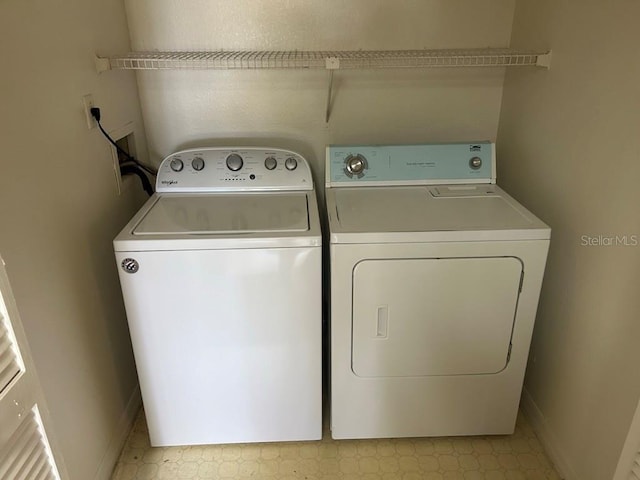 washroom with baseboards, washer and clothes dryer, and light floors