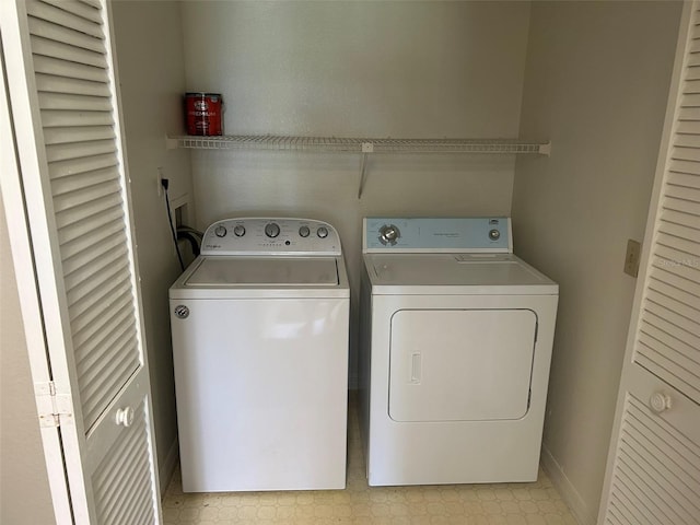 clothes washing area with laundry area, baseboards, light floors, and washer and dryer