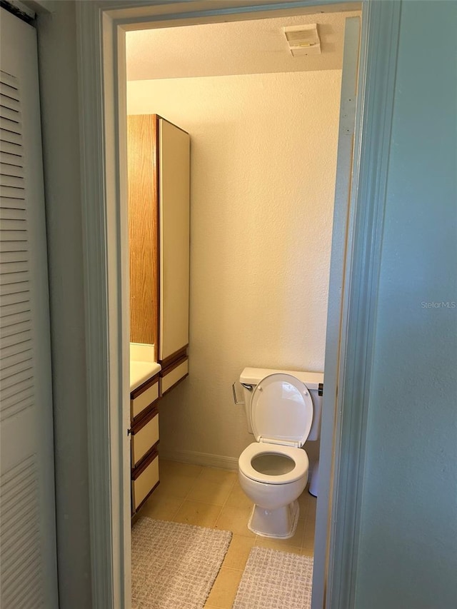 bathroom featuring baseboards, vanity, toilet, and tile patterned floors