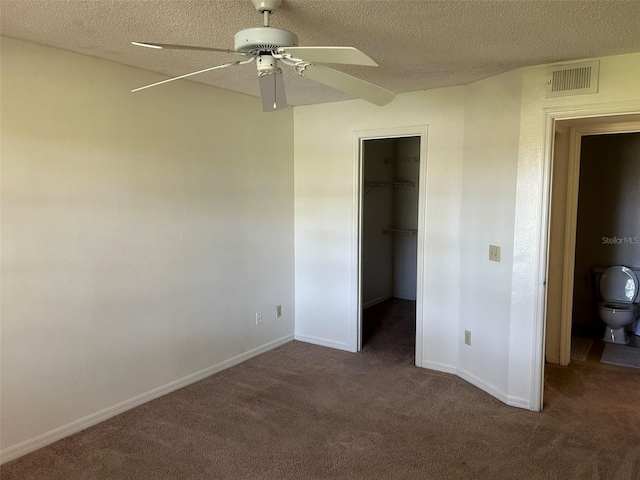 unfurnished bedroom with a closet, carpet, a walk in closet, and a textured ceiling