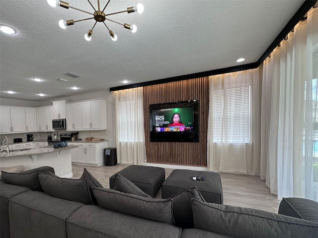 living area featuring a textured ceiling, visible vents, and light wood-style floors
