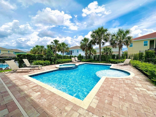 view of swimming pool featuring a patio, fence, and a pool with connected hot tub