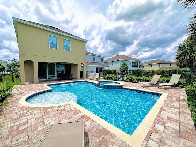 view of pool with a patio area, a pool with connected hot tub, and fence