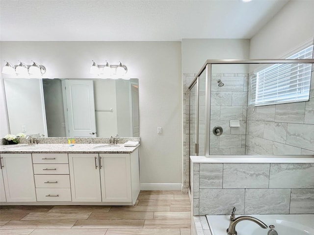 bathroom with wood finish floors, a sink, a bath, double vanity, and a stall shower