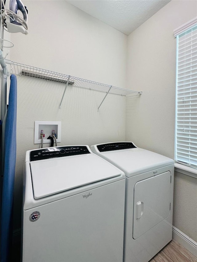 laundry room with light wood-type flooring, laundry area, baseboards, and separate washer and dryer
