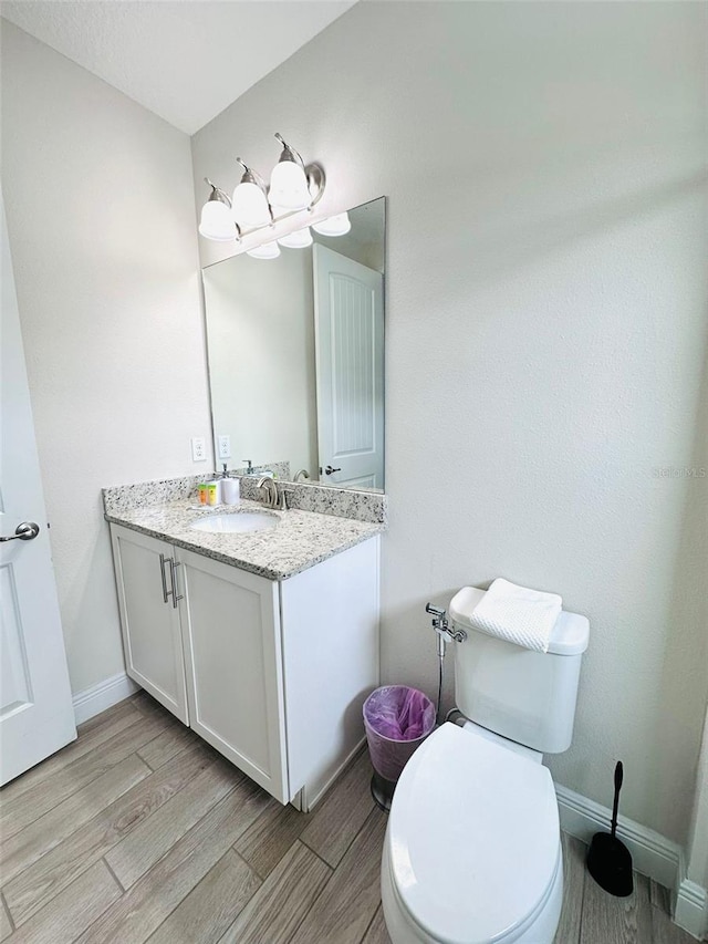 bathroom with wood tiled floor, baseboards, vanity, and toilet