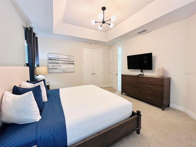 bedroom with a tray ceiling, a notable chandelier, visible vents, light carpet, and baseboards