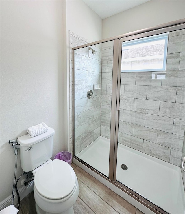 full bath featuring a stall shower, toilet, and wood finished floors