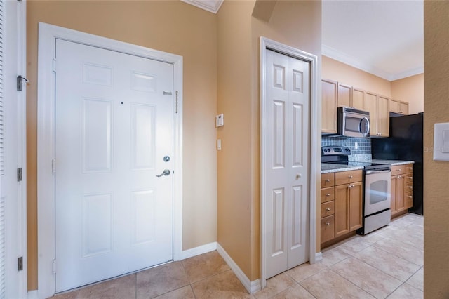 kitchen with ornamental molding, appliances with stainless steel finishes, light tile patterned flooring, and backsplash