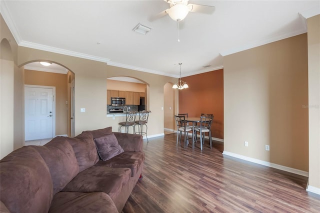 living room with ceiling fan, wood finished floors, visible vents, baseboards, and crown molding