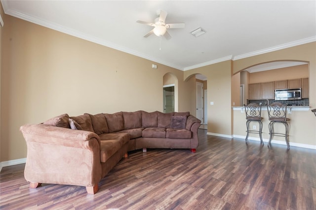 living area with baseboards, crown molding, arched walkways, and dark wood-type flooring