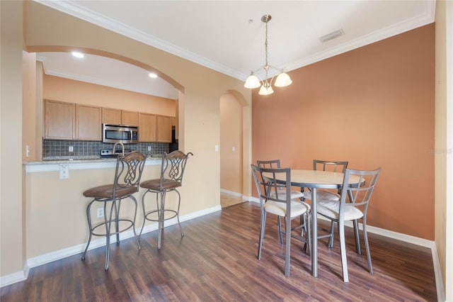 dining area with arched walkways, dark wood finished floors, visible vents, and baseboards