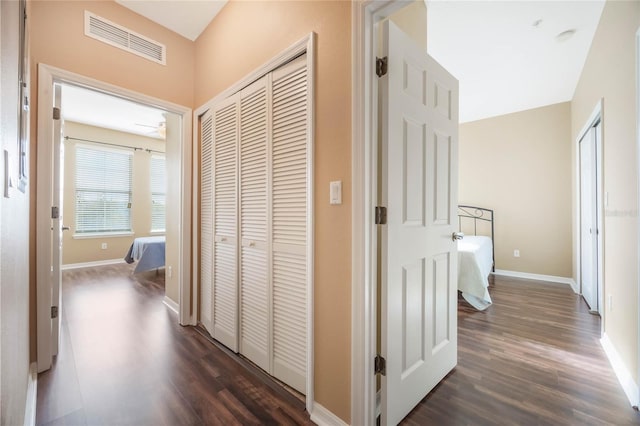 hallway featuring baseboards, visible vents, and dark wood-type flooring