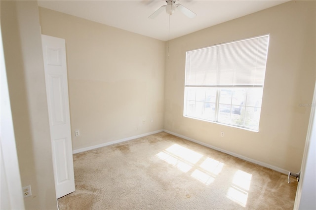 carpeted empty room featuring ceiling fan and baseboards