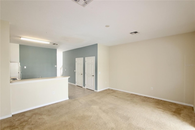 empty room featuring light colored carpet, visible vents, and baseboards