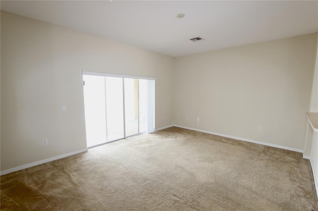 unfurnished room featuring carpet, visible vents, and baseboards