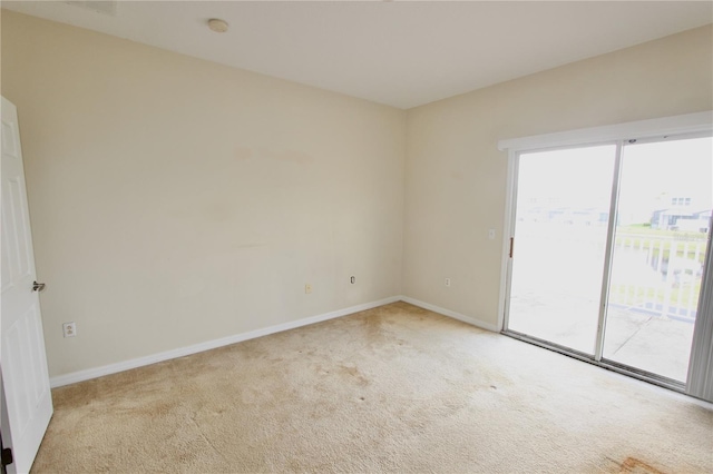 spare room with light colored carpet and baseboards