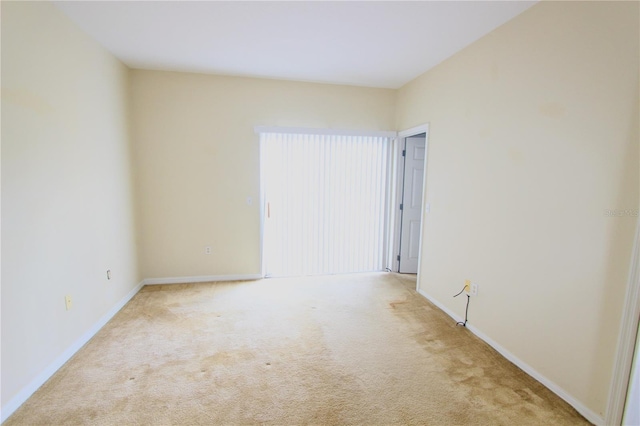 empty room featuring baseboards and light colored carpet