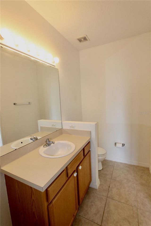 bathroom featuring toilet, vanity, baseboards, visible vents, and tile patterned floors