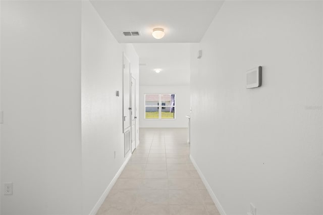 hallway with light tile patterned floors, baseboards, and visible vents