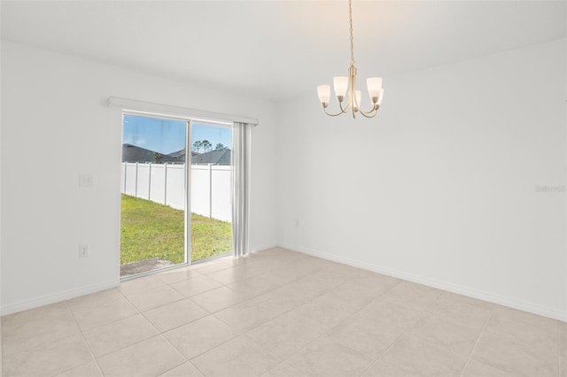 empty room featuring an inviting chandelier and baseboards