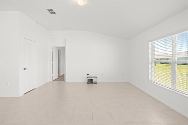 empty room with visible vents, vaulted ceiling, and baseboards