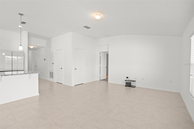 unfurnished living room featuring baseboards, visible vents, and a wealth of natural light