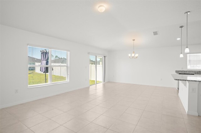 unfurnished living room with a chandelier, visible vents, plenty of natural light, and light tile patterned floors