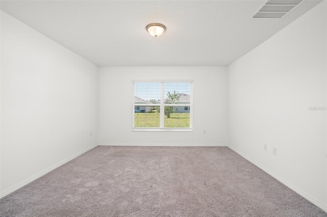 carpeted spare room featuring visible vents and baseboards