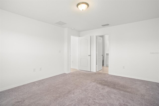 spare room featuring baseboards, visible vents, and light colored carpet