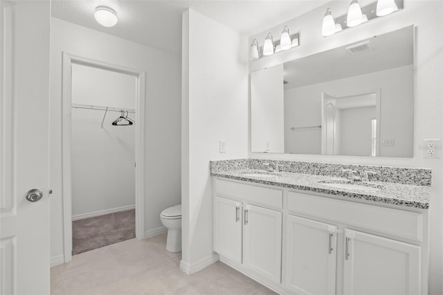 bathroom featuring toilet, double vanity, a sink, and visible vents