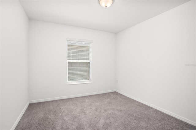 unfurnished room with carpet flooring and baseboards