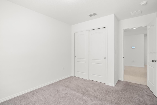 unfurnished bedroom with a closet, visible vents, baseboards, and carpet flooring