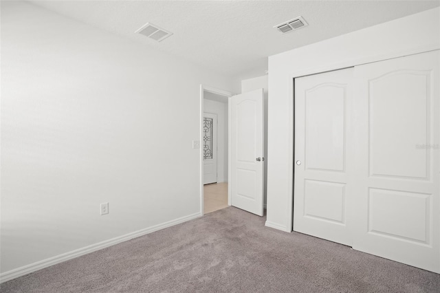 unfurnished bedroom with a closet, visible vents, baseboards, and carpet flooring