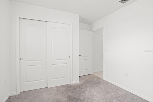 unfurnished bedroom with carpet floors, a closet, visible vents, and baseboards