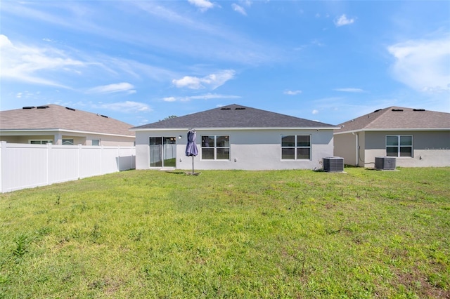 back of house with central AC, a lawn, fence, and stucco siding