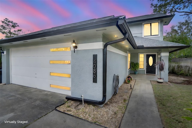 view of front of home with roof with shingles, fence, and stucco siding