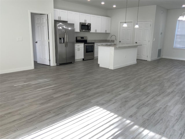 kitchen with light wood finished floors, visible vents, appliances with stainless steel finishes, open floor plan, and white cabinetry