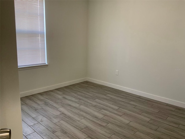 spare room featuring baseboards and wood finished floors