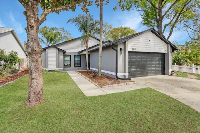 view of front of property with a front lawn, fence, concrete driveway, stucco siding, and an attached garage