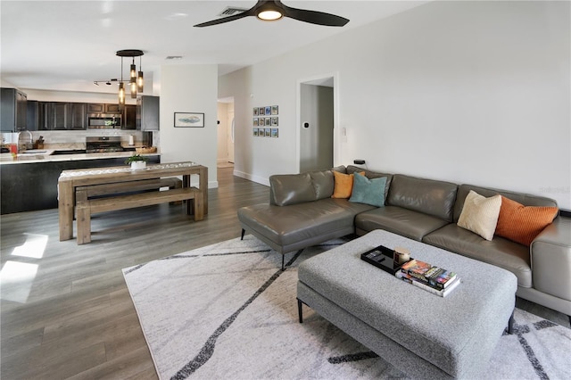 living room featuring ceiling fan, visible vents, lofted ceiling, and wood finished floors