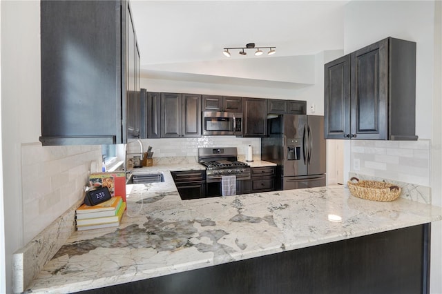 kitchen featuring light stone counters, stainless steel appliances, lofted ceiling, and a sink