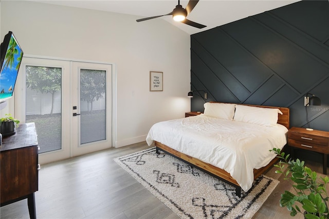 bedroom with lofted ceiling, wood finished floors, french doors, baseboards, and access to exterior