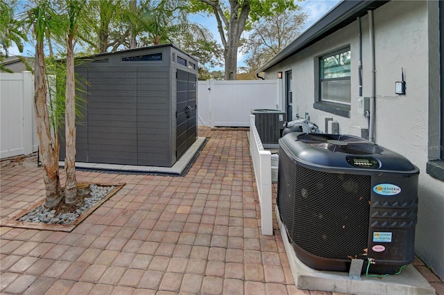 view of patio featuring an outbuilding, central AC unit, a storage shed, and a fenced backyard