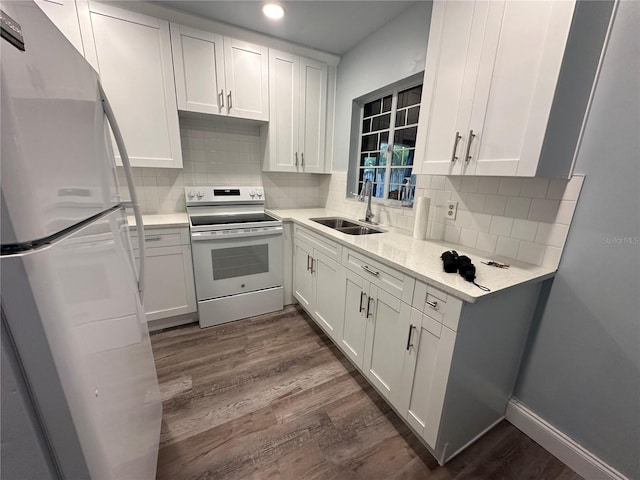 kitchen with white electric range, a sink, white cabinetry, freestanding refrigerator, and dark wood finished floors