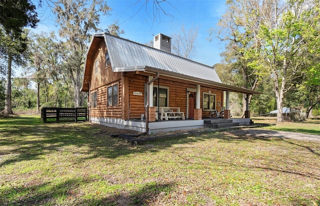 view of front of property with covered porch, a gambrel roof, a chimney, a front lawn, and metal roof